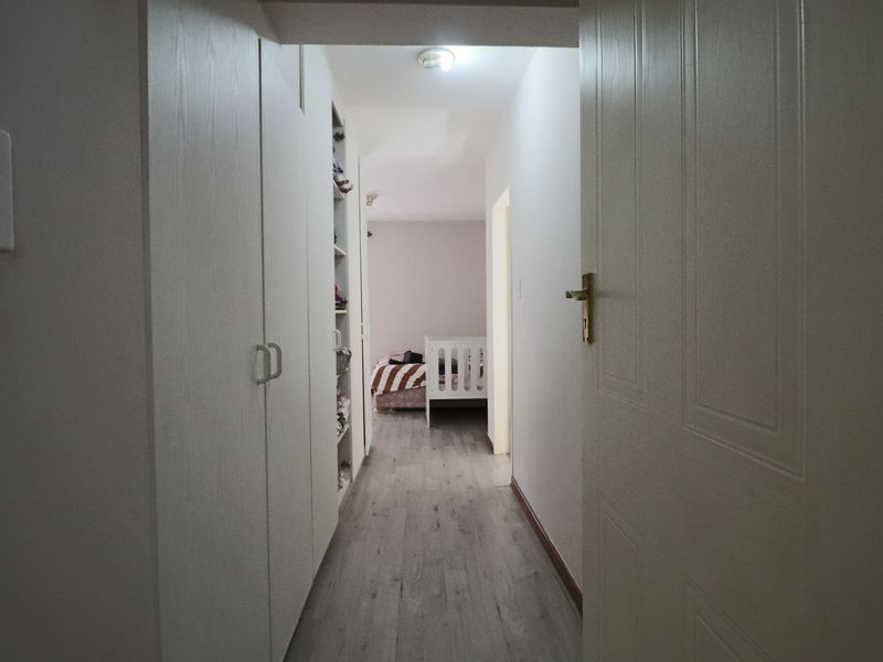 A functional hallway featuring built-in storage cupboards and modern laminate flooring, providing access to the bedroom area.