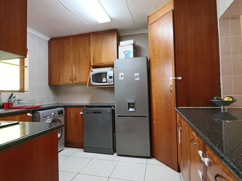 A functional kitchen featuring wood-finish cabinetry, granite countertops, tiled backsplash, and tiled flooring, offering ample storage and workspace.