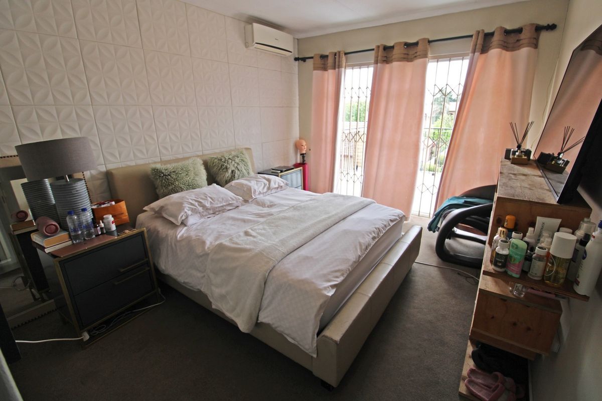 A bedroom featuring textured wall paneling, a split-system air conditioner, and a sliding glass door with security gate access to the exterior.