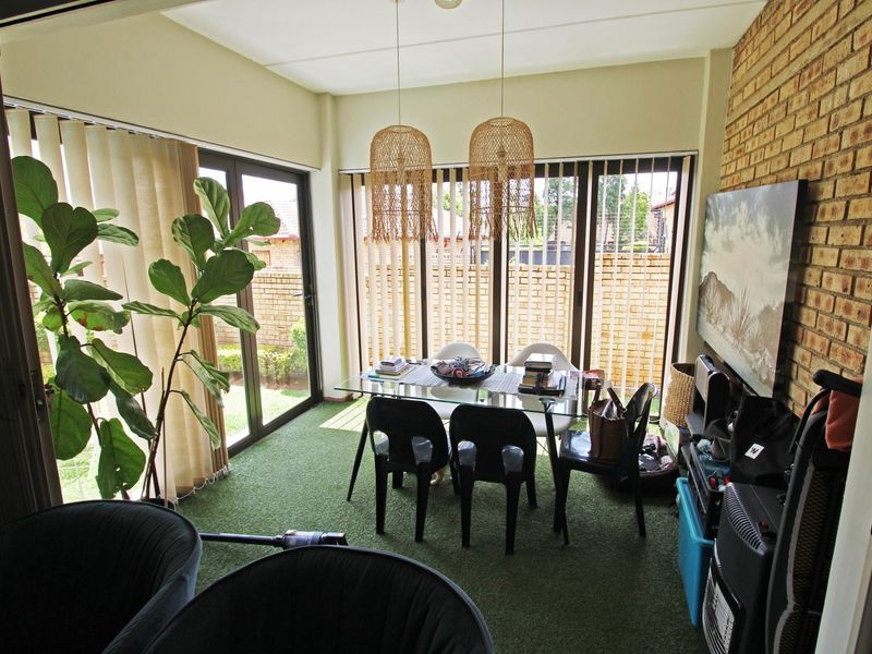 Enclosed patio area featuring exposed brick wall, artificial grass flooring, and large sliding glass doors providing access to the garden.