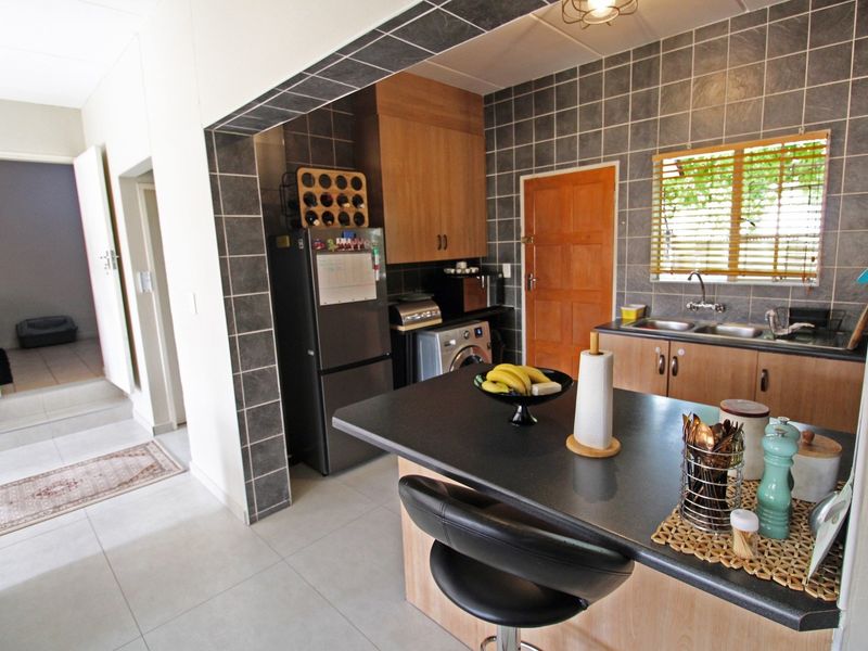 Functional kitchen featuring built-in cabinetry, a double basin sink, tiled backsplash, and a convenient breakfast bar area.