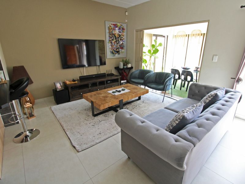 A well-maintained living room featuring tiled flooring and large sliding glass doors that provide natural light and access to the outdoor patio area.