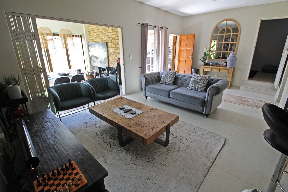Spacious living room featuring large format floor tiles, neutral walls, and sliding glass doors that provide seamless access to the adjacent dining area.