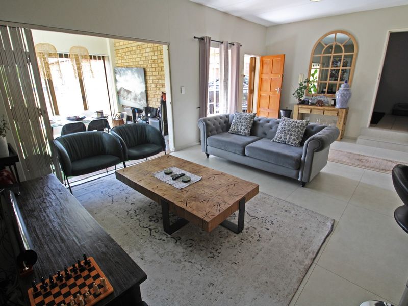 Spacious living room featuring large format floor tiles, neutral walls, and sliding glass doors that provide seamless access to the adjacent dining area.