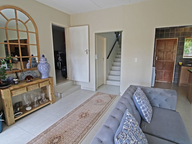Open plan living area featuring tiled flooring, a staircase leading to the upper level, and a view into the adjacent kitchen space.