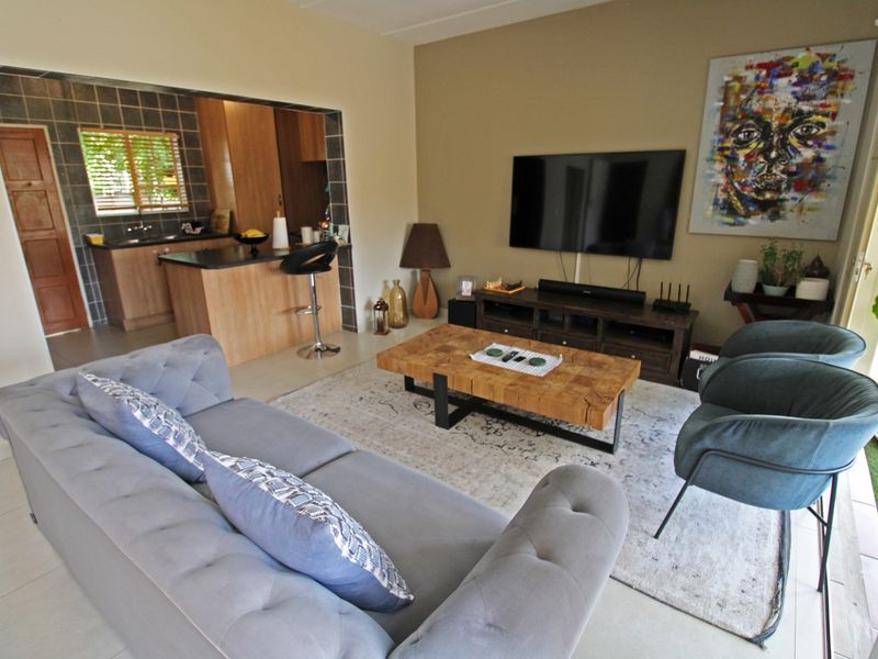 Open plan living area featuring a connected kitchen with wood-look cabinetry, dark countertops, and tiled flooring throughout the combined space.