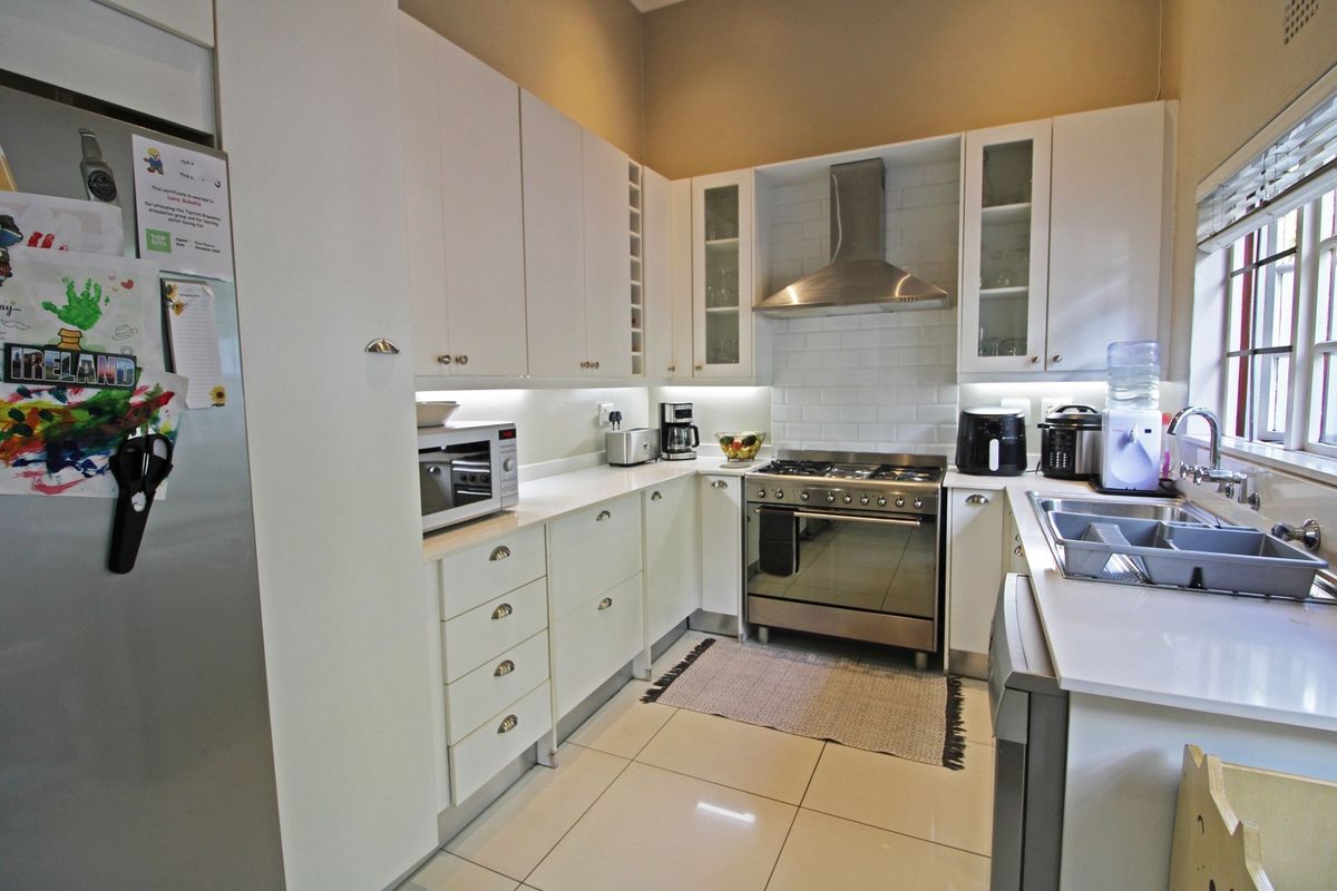 Modern kitchen featuring white cabinetry, subway tile backsplash, stainless steel gas stove with extractor fan, and tiled flooring.