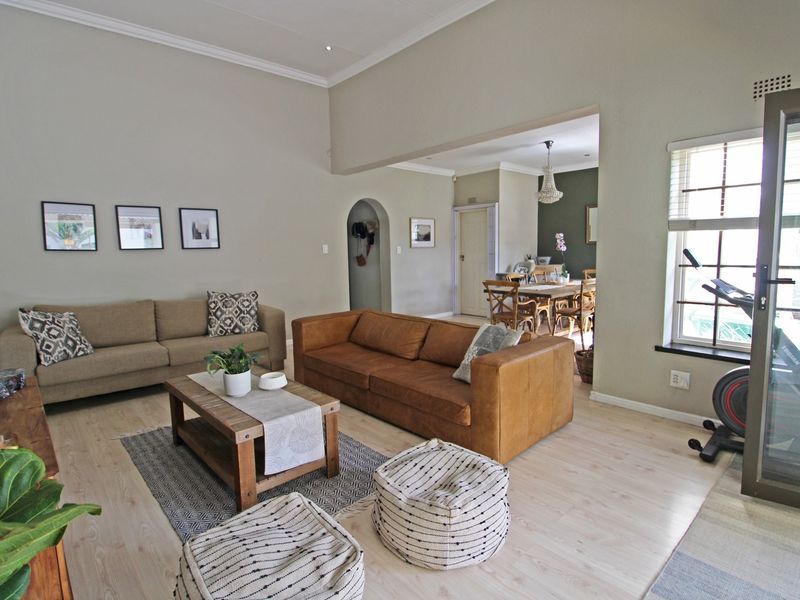 Spacious open-plan living area featuring light laminate flooring, high ceilings with coved cornicing, and a seamless transition to the adjacent dining space.