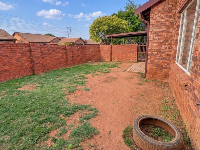 A private rear garden area featuring a brick boundary wall, an external water tap, and a small covered patio section.
