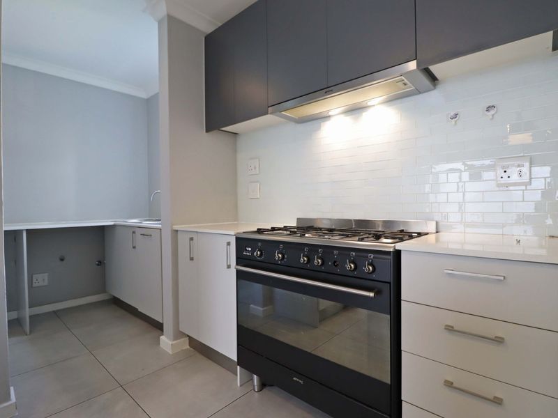 Modern kitchen featuring dark upper cabinetry, white lower cabinets, quartz countertops, subway tile backsplash, and a built-in gas stove with extractor fan.