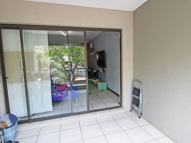 A covered balcony featuring tiled flooring and a large sliding glass door providing access to the interior living space.