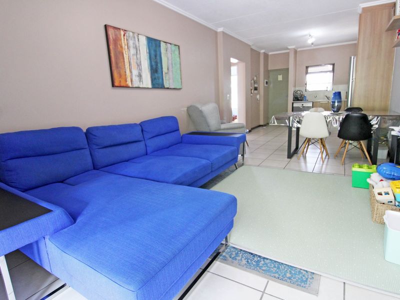 Open-plan living and dining area featuring tiled flooring and a functional kitchen with built-in cabinetry and appliances.