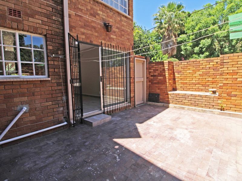 A private rear courtyard featuring brick paving, a built-in brick bench, and secure access to the apartment interior.