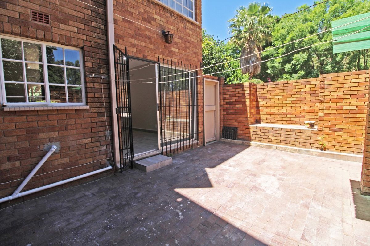 A private rear courtyard featuring brick paving, a built-in brick bench, and secure access to the apartment interior.
