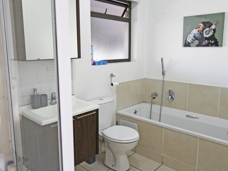 A functional bathroom featuring a built-in vanity, a bathtub with shower attachment, and a separate shower enclosure with tiled finishes.