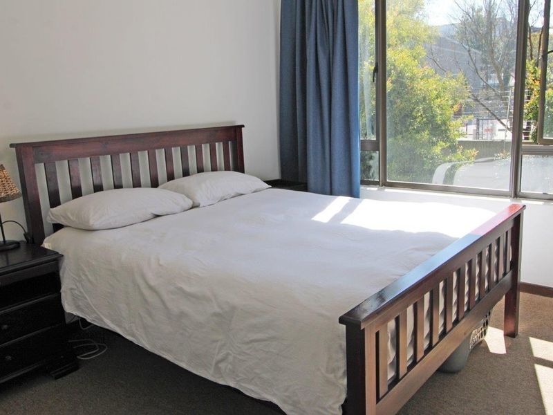 A bright bedroom featuring large windows that provide natural light and a view of the surrounding greenery.