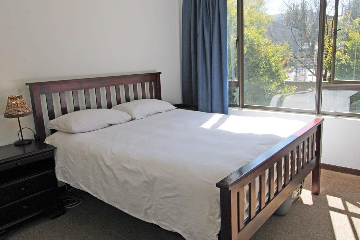 A bright bedroom featuring large windows that provide natural light and a view of the surrounding greenery.