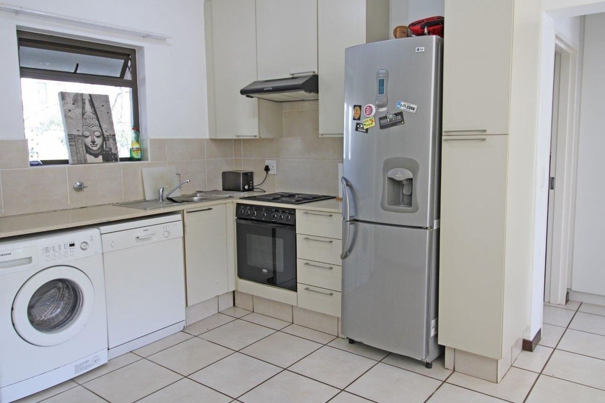 Functional kitchen featuring built-in cabinetry, tiled backsplash, integrated oven and hob, and tiled flooring with space for under-counter appliances.