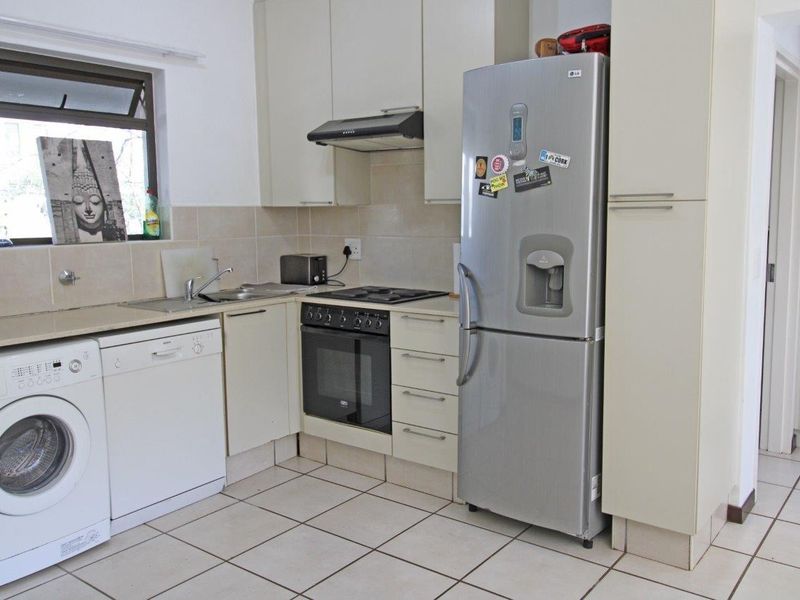 Functional kitchen featuring built-in cabinetry, tiled backsplash, integrated oven and hob, and tiled flooring with space for under-counter appliances.