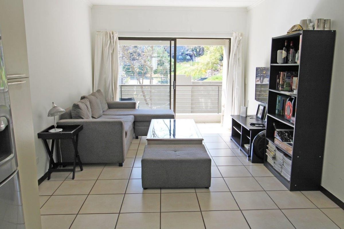 A bright living room featuring tiled flooring and a large sliding glass door that provides direct access to an outdoor balcony area.