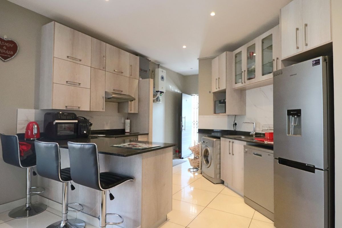 Modern kitchen featuring light wood-finish cabinetry, granite countertops, tiled flooring, and integrated space for appliances, offering a functional and contemporary cooking area.