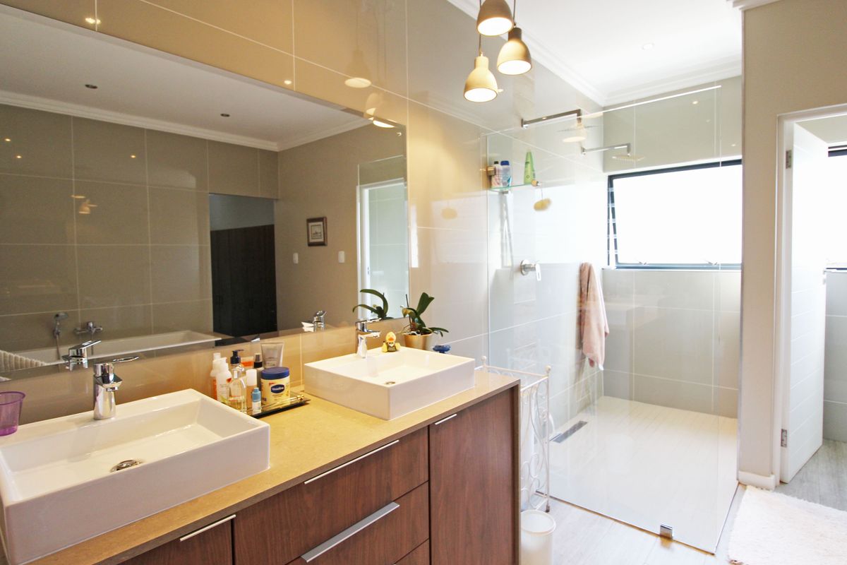 Modern bathroom featuring a double vanity with vessel sinks, a large wall-to-wall mirror, and a spacious walk-in shower with glass enclosure.