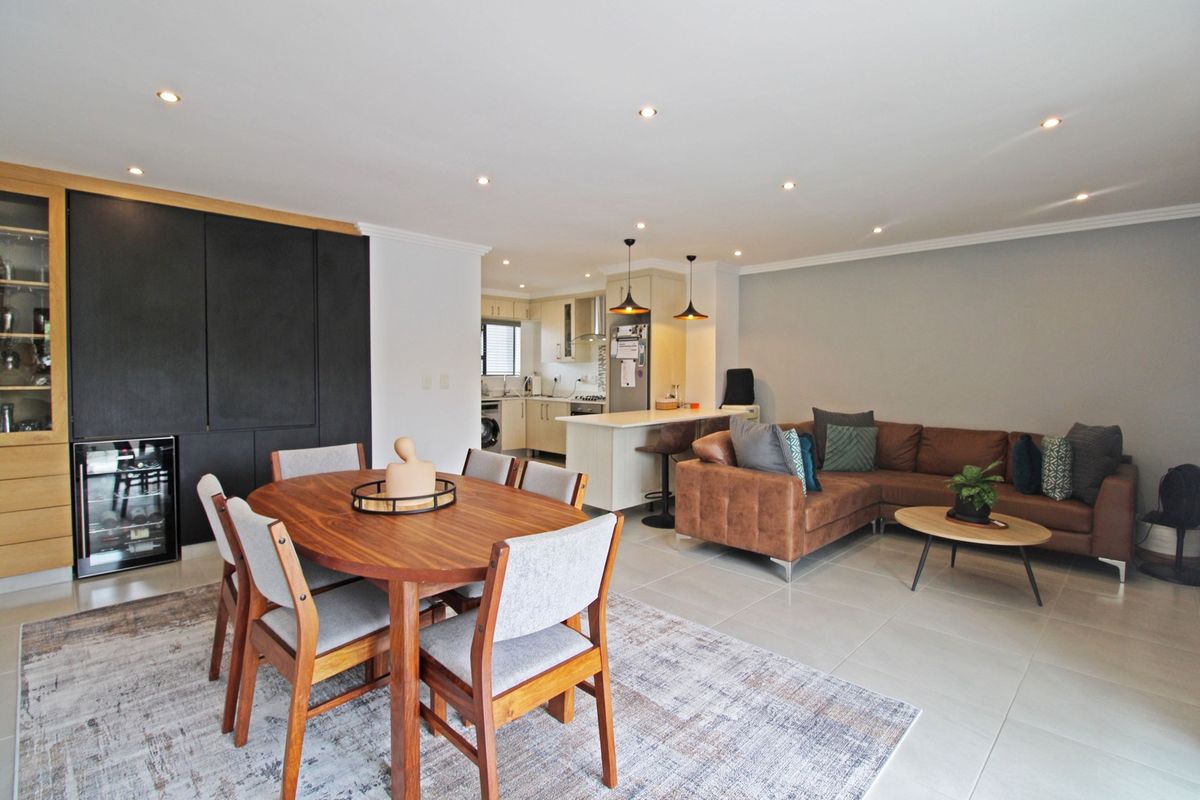 Spacious open-plan living and dining area featuring a modern kitchen with an island, integrated wine cooler, and sleek built-in cabinetry.