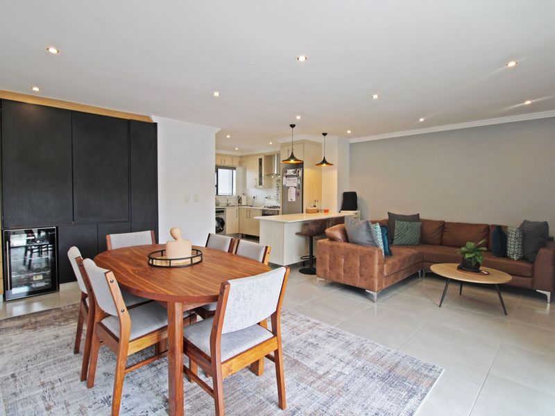 Spacious open-plan living and dining area featuring a modern kitchen with an island, integrated wine cooler, and sleek built-in cabinetry.