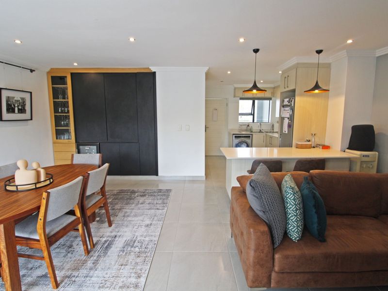 Spacious open-plan living and dining area featuring modern cabinetry, a functional kitchen island, and contemporary lighting throughout.