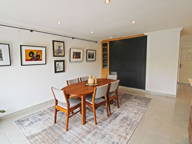 A well-maintained dining area featuring tiled flooring, recessed downlights, a picture hanging rail, and sleek built-in cabinetry.