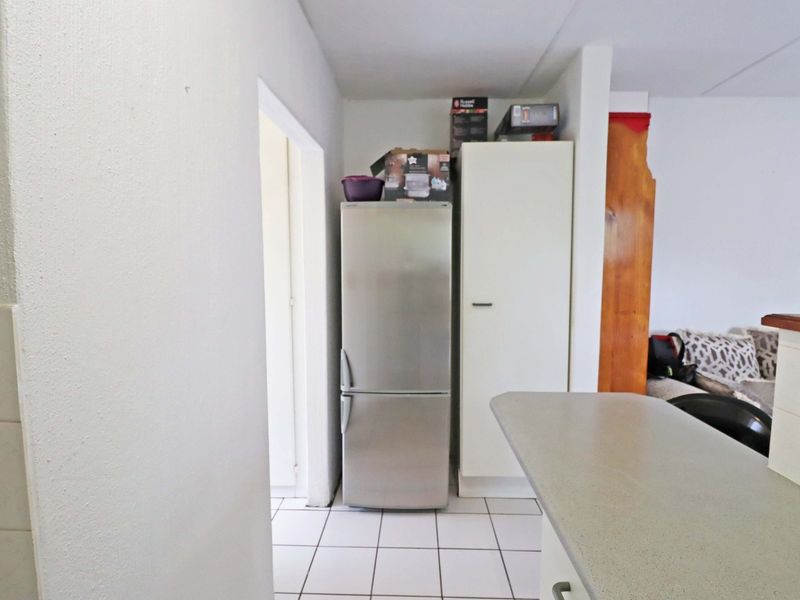A functional kitchen area featuring tiled flooring, built-in cabinetry, and a countertop, providing a practical layout for daily use.