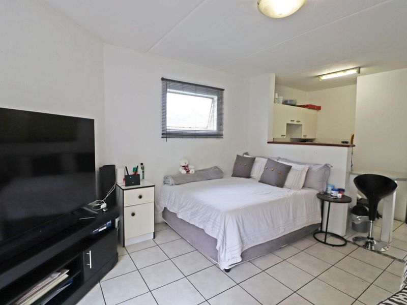 Open-plan studio apartment featuring tiled flooring, a compact kitchen area, and a functional living and sleeping space with natural light.