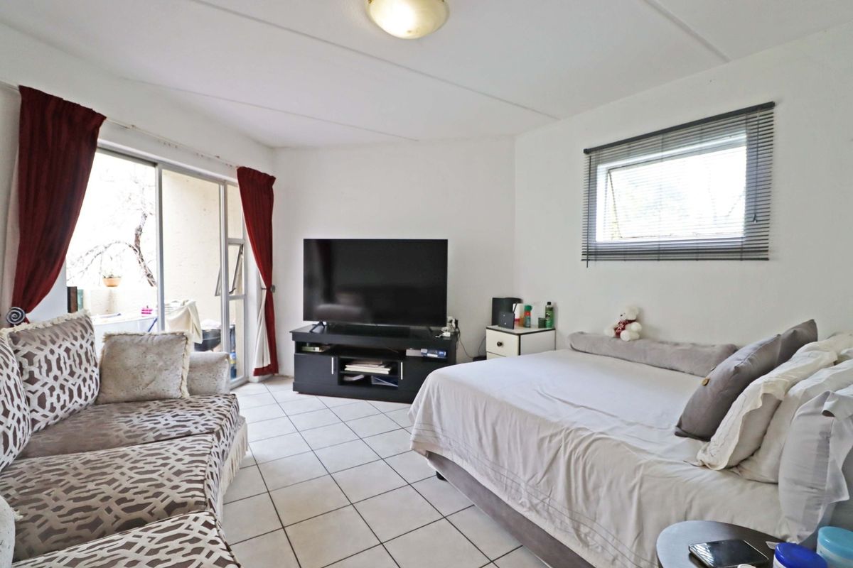 A functional bedroom featuring tiled flooring, a sliding glass door providing access to an outdoor area, and an awning window for natural light.
