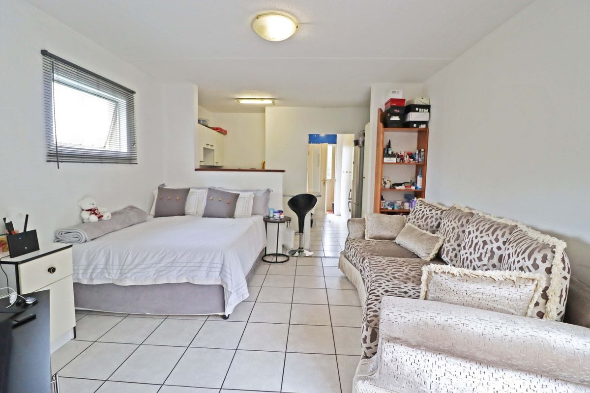 Open-plan studio apartment featuring tiled flooring, a functional kitchen area, and a combined living and sleeping space with natural light.