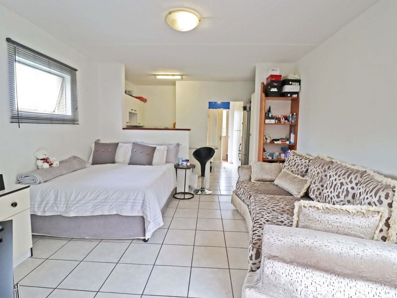 Open-plan studio apartment featuring tiled flooring, a functional kitchen area, and a combined living and sleeping space with natural light.