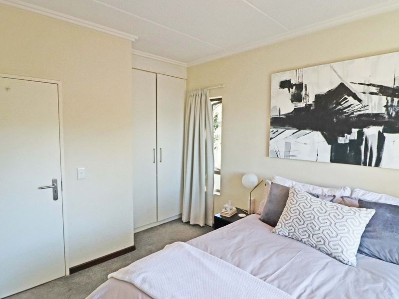 A well-maintained bedroom featuring neutral walls, carpeted flooring, and a built-in wardrobe with clean finishes.