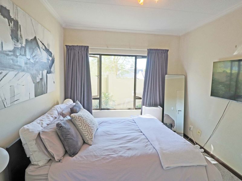 A bedroom featuring carpeted flooring, a casement window with curtains, and coved ceiling detailing.