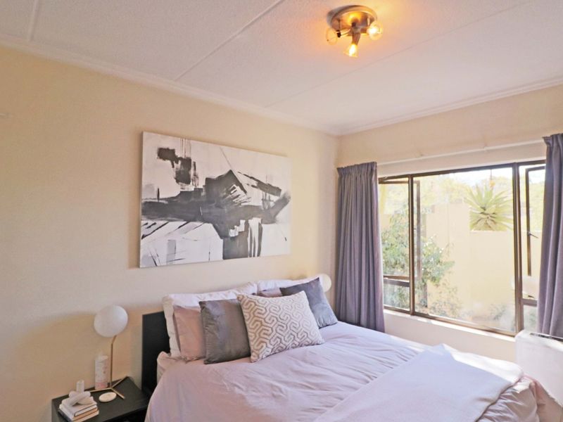 A well-lit bedroom featuring large windows that provide natural light and a view of the exterior surroundings.
