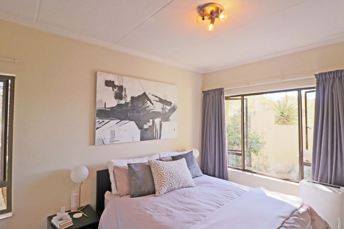 A well-lit bedroom featuring large windows that provide natural light and a view of the exterior surroundings.