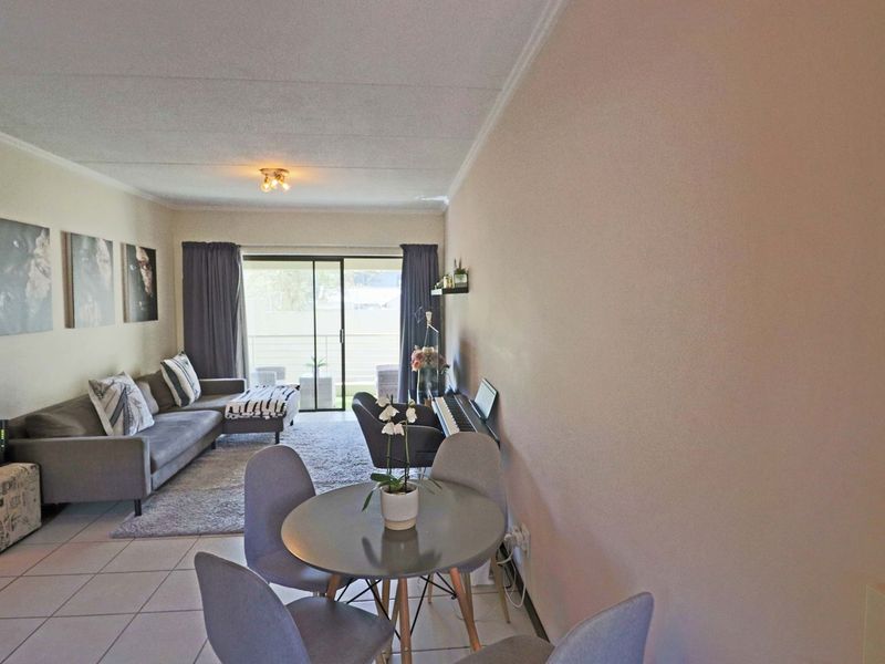 Open plan living and dining area featuring tiled flooring, neutral walls, and a sliding glass door leading to an outdoor balcony space.