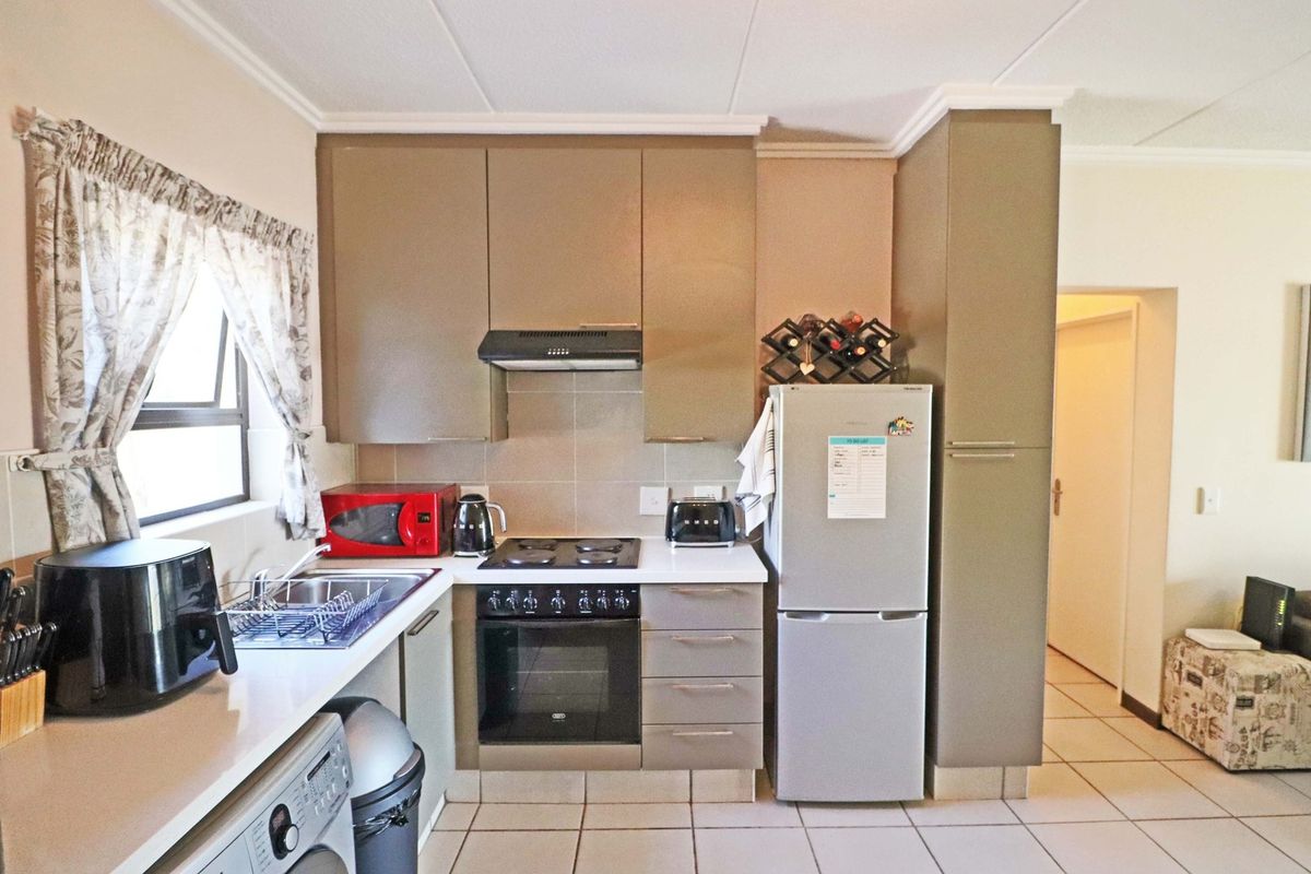 A functional kitchen featuring built-in cabinetry, an electric hob with extractor fan, built-in oven, and tiled flooring.