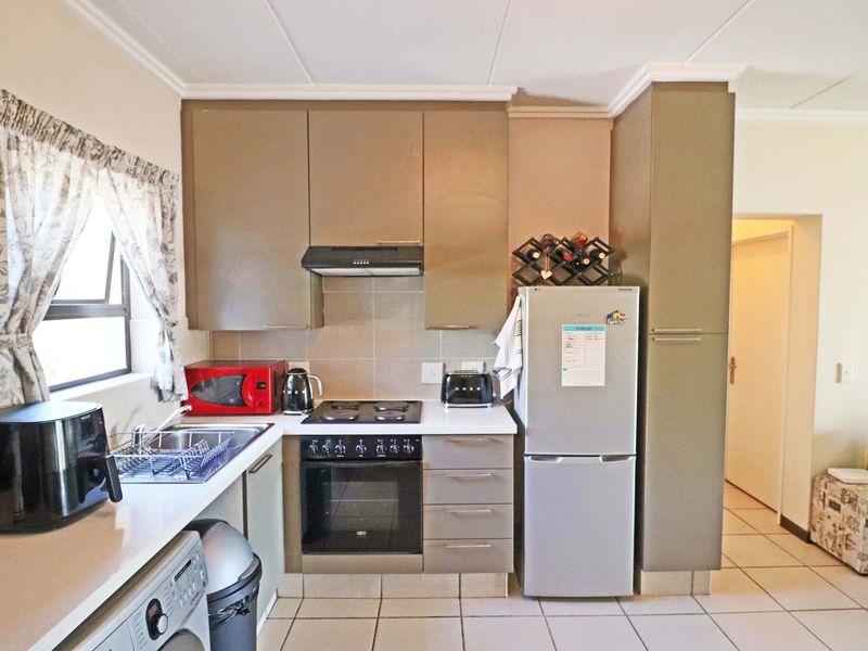A functional kitchen featuring built-in cabinetry, an electric hob with extractor fan, built-in oven, and tiled flooring.