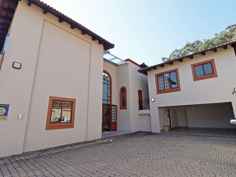 Front elevation of a multi-story house featuring a paved driveway, double garage, and distinctive arched architectural detailing.