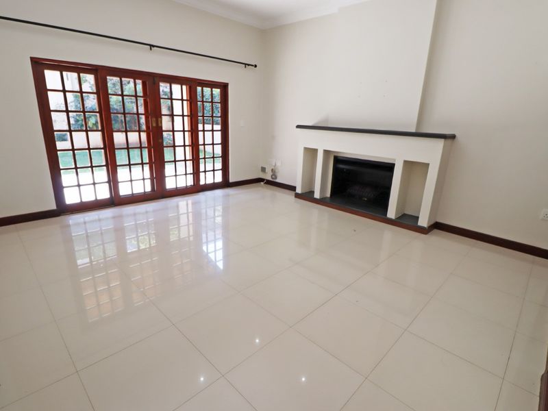 Spacious living room featuring polished tile flooring, a built-in fireplace, and large wooden sliding doors providing access to the garden.