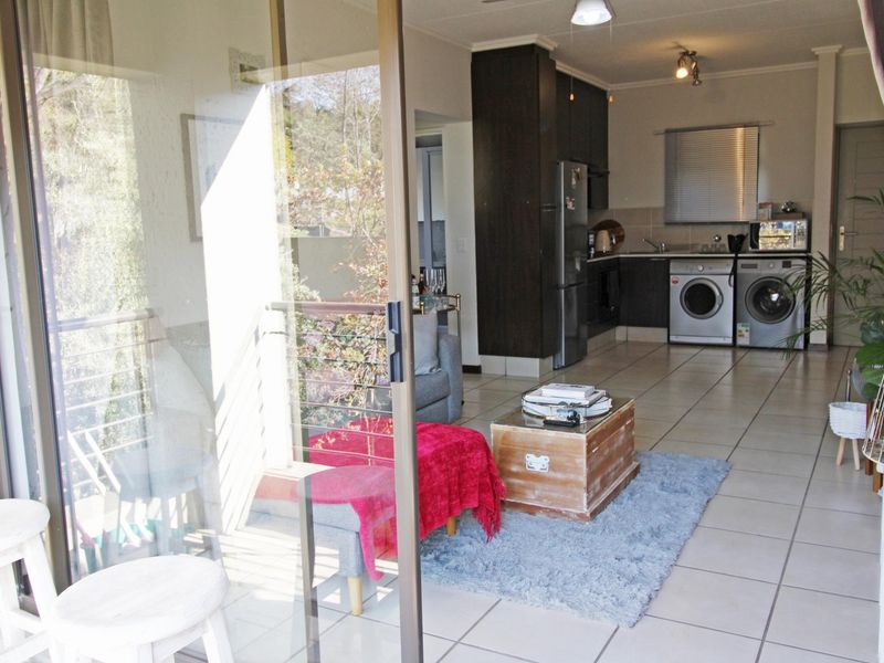 Open-plan living area featuring tiled floors, a modern kitchen with built-in cabinetry, and direct access to a balcony through sliding glass doors.