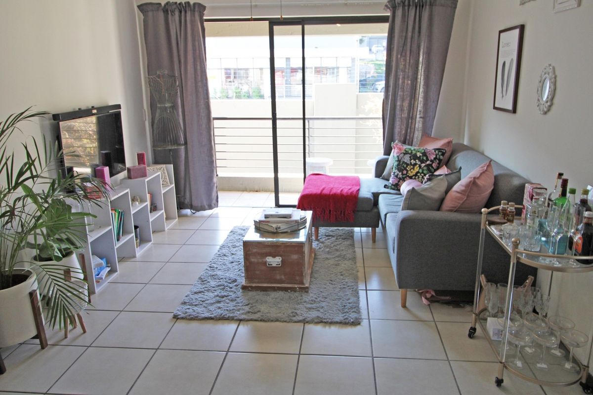 A bright living room featuring tiled flooring and a large sliding glass door providing access to an attached balcony.