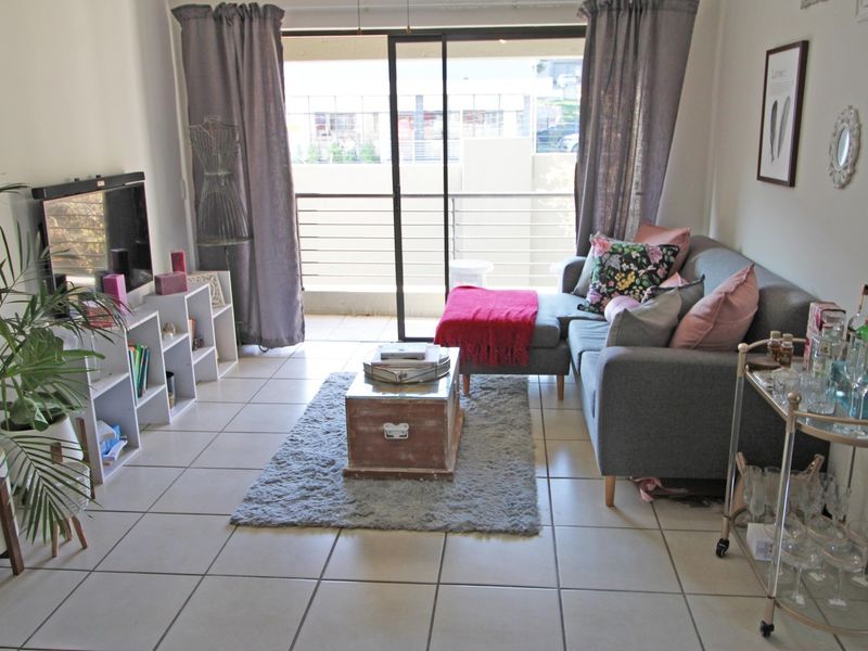 A bright living room featuring tiled flooring and a large sliding glass door providing access to an attached balcony.