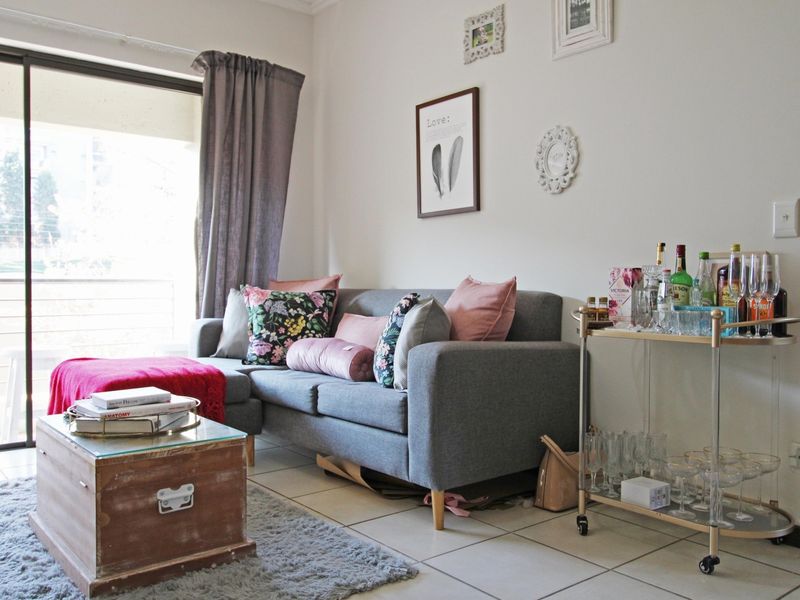A living room area featuring tiled flooring and a large sliding glass door providing access to an outdoor space.