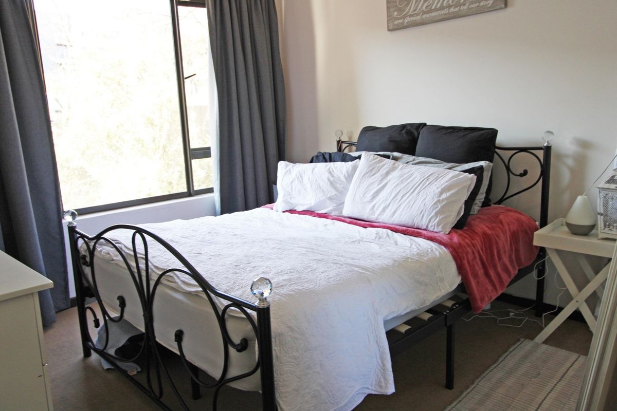 A functional bedroom featuring a large window that provides natural light and carpeted flooring throughout.