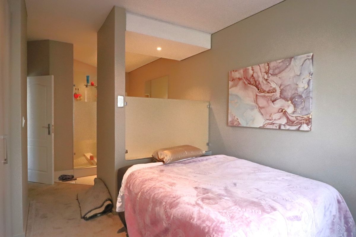 A bedroom featuring a partition wall separating the sleeping area from an en-suite bathroom, with neutral wall tones and recessed ceiling lighting.